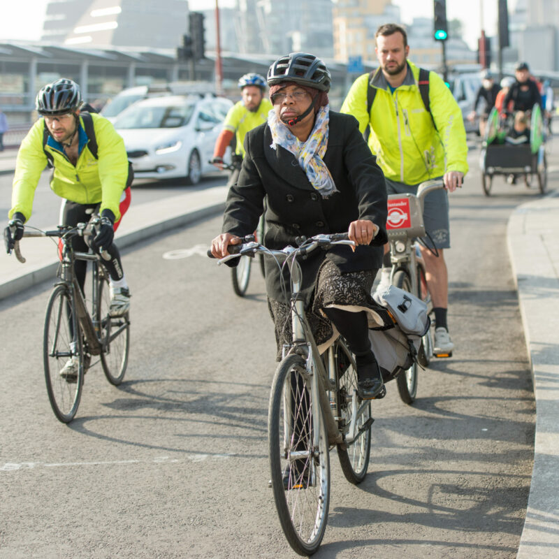 Woman cycling on cycle lane in skirt (cycle superhighway)
