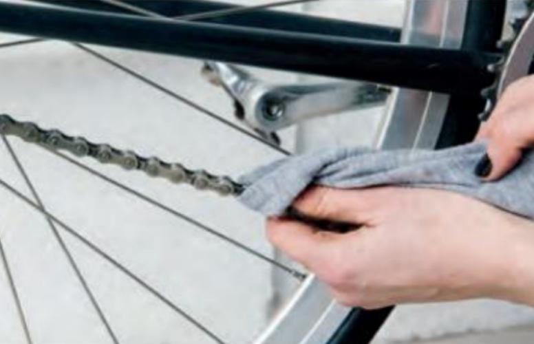 Woman bike mechanic cleaning bike chain