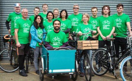 A group of Climate Safe Streets champions gathered around a cargo bike all wearing green tee shirts.