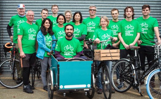 A group of Climate Safe Streets champions gathered around a cargo bike all wearing green tee shirts.