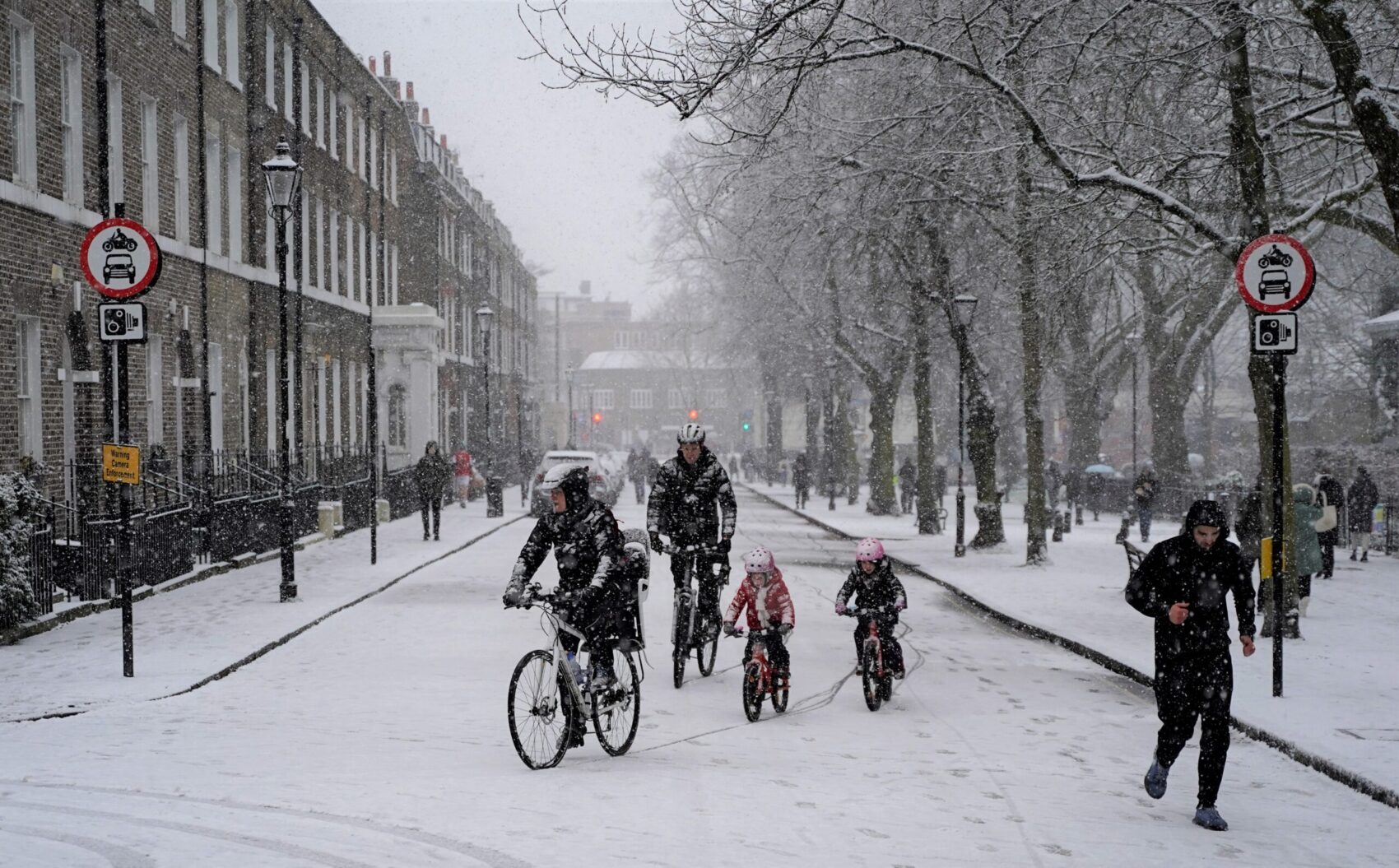 Children and parents - family cycling in the snow in Low Traffic Neighbourhood (LTN)