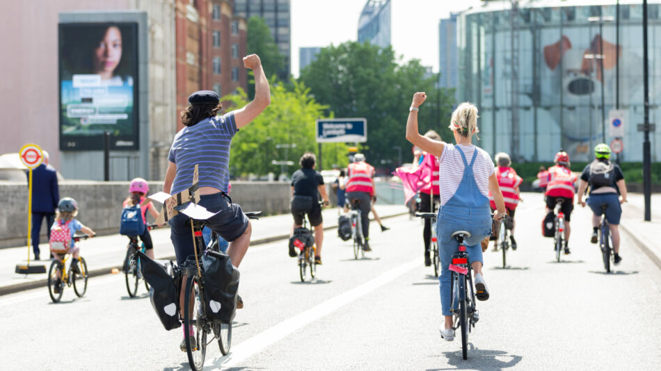 LCC protest ride woman cycling with fist in air