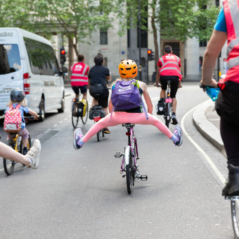 Children cycling with legs out - kids playing