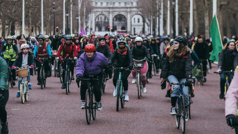 Woman cycling towards camera with big group of people cycling at LCC protest