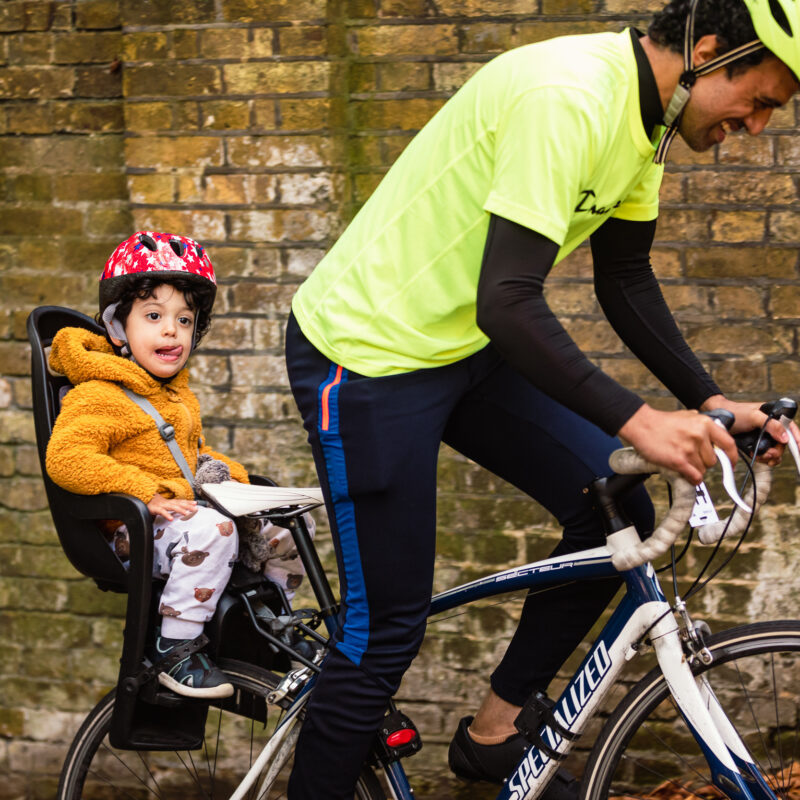Man with child in seat on back of bike at Urban Hill Climb challenge event