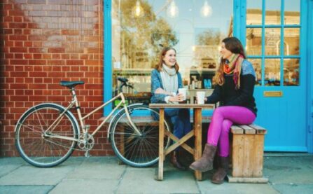 Women at cafe with bike, sitting having coffee